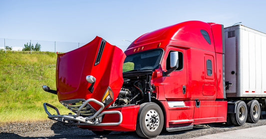 A red semitruck towing a white shipping container is parked on the side of the road with its hood open.