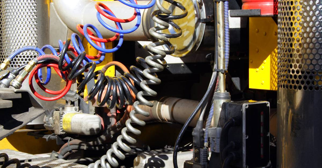 A semi-truck's air braking system. Colorful brake cables and wires connect the truck cab to the air system.