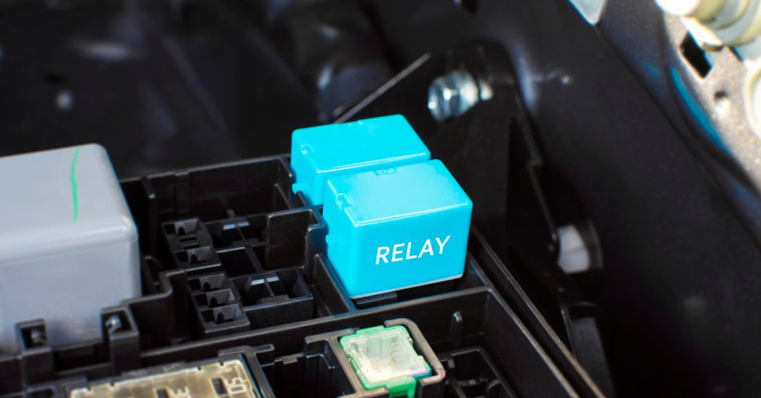 A light blue electronic automotive relay is plugged into the engine socket box. The word "RELAY" is on the device.