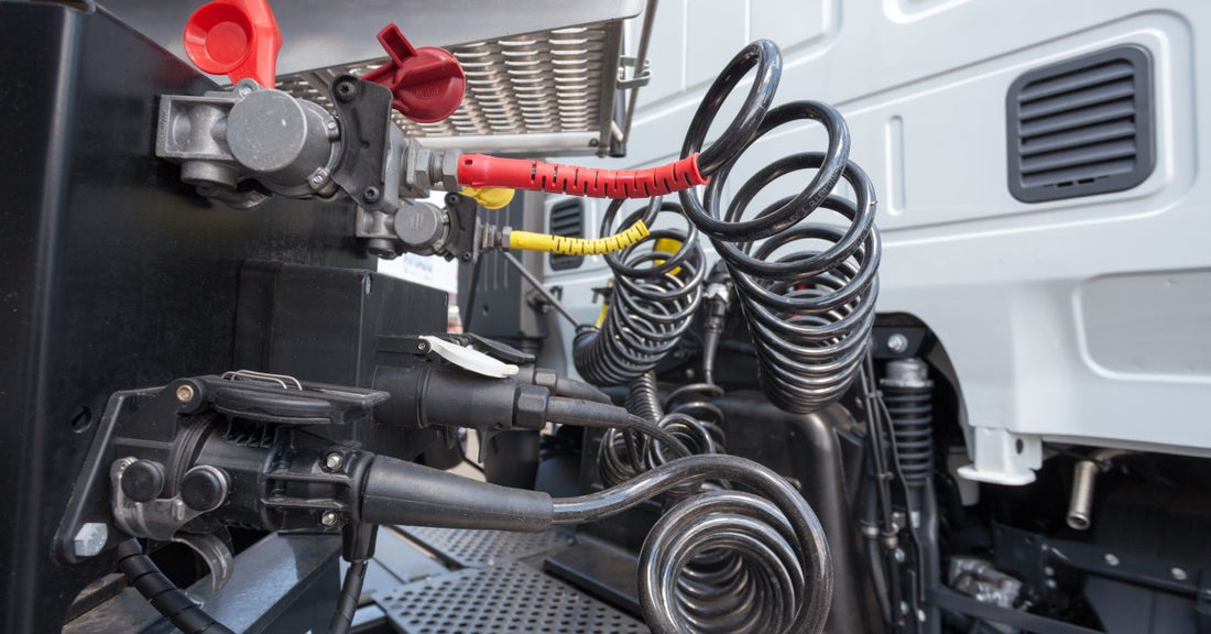 A standard semi-truck air brake system attached to a truck cab. Coiled compressed air hoses connect the system to the cab.