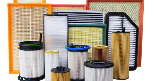 A wide selection of automotive oil filters of various shapes, sizes, and colors, against a white background.