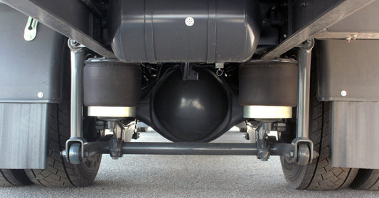 A close-up view of the undercarriage of a semi-truck, exposing the air suspension system and large airbags.